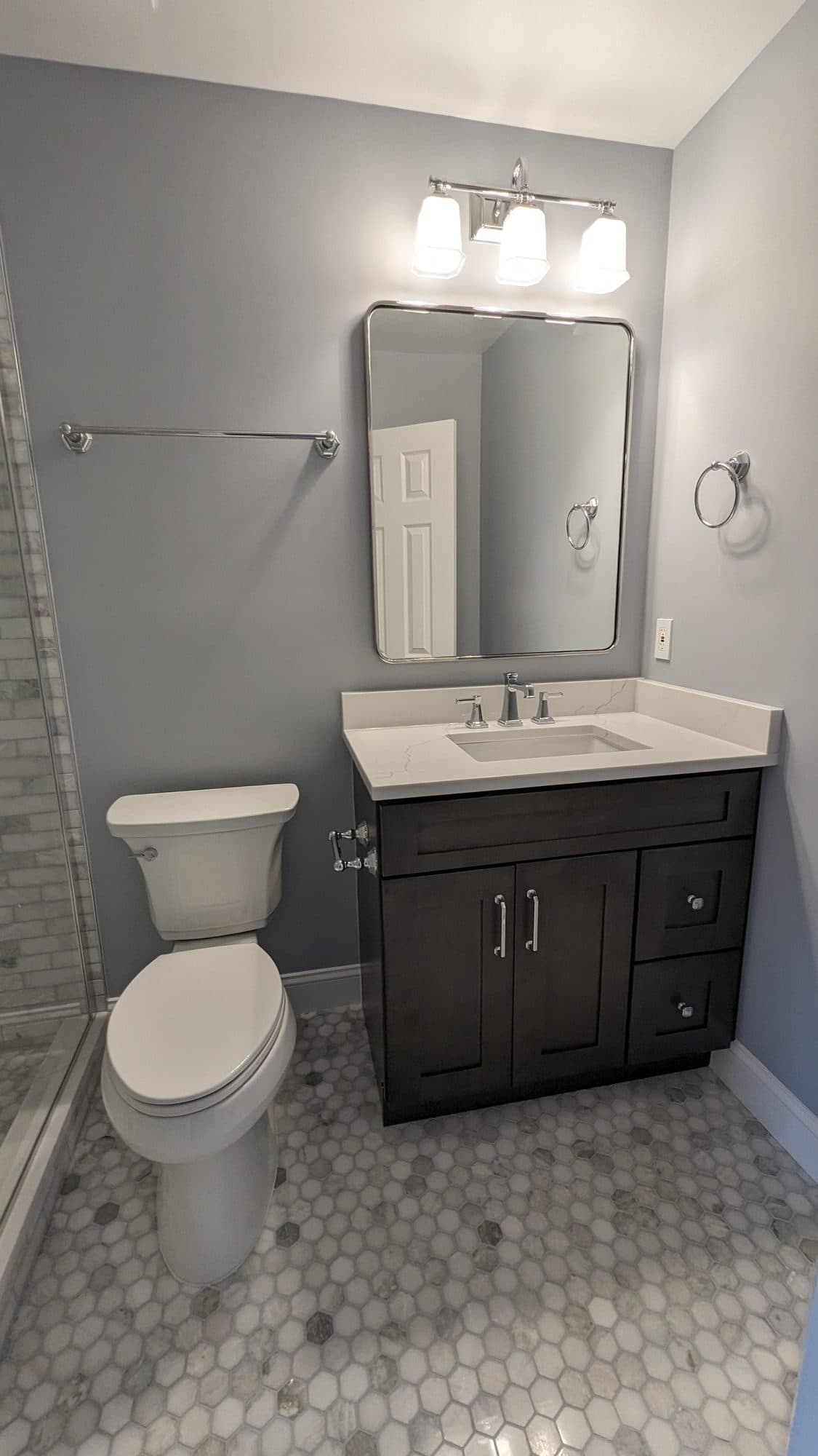 Vanity with chrome fixtures, marble countertop, and dark cabinetry