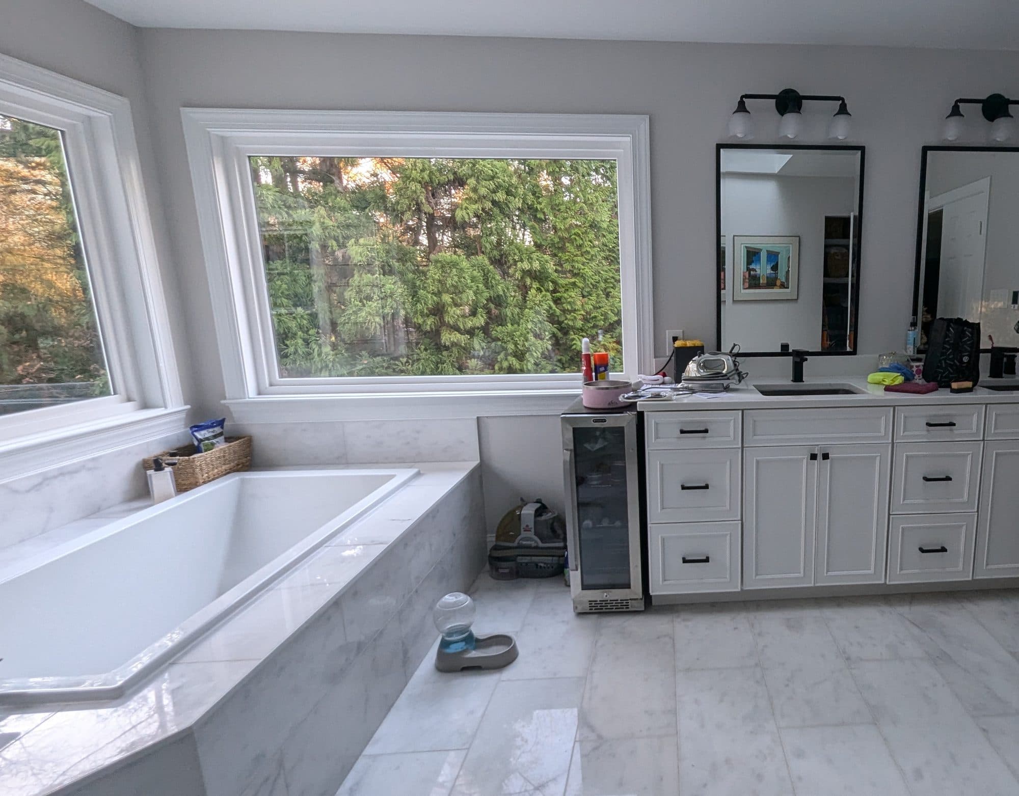 Primary bathroom with a soaking tub, vanity, and a large window overlooking trees